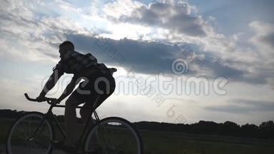 年轻男子骑着老式自行车的剪影，背景是美丽的天空。 骑自行车的人